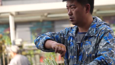 Kunming,-Yunnan,-China---September-1,-2022:-a-man-florist-busy-tidying-up-their-flowers-at-the-Kunming-Dounan-Flower-Market