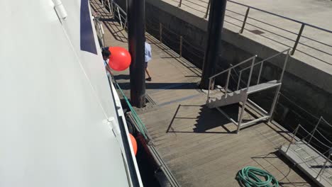 sailors-working-on-the-arrival-of-the-boat-mooring-the-boat-at-the-pier-of-the-Cíes-Islands-on-a-sunny-day-in-the-Rías-Baixas,-shot-blocked-down,-Pontevedra,-Galicia,-Spain