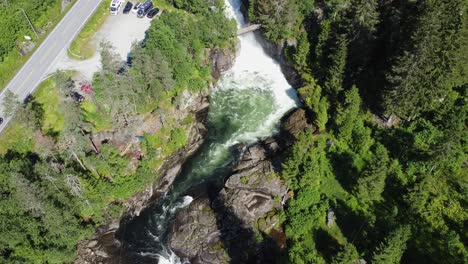 Person-riding-zipline-above-the-stranda-river-in-Voss-climbing-and-Zipline-park-Norway---Aerial-looking-down-at-river-and-person-during-summer-vacation--Voss-Active-western-Norway