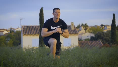 Tracking-shot-of-male-athlete-making-Lunge-sidestep-outdoors-in-garden,-closeup