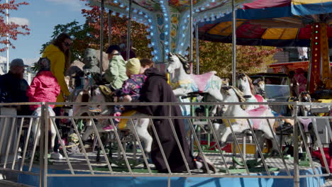 Toma-Estática-En-Cámara-Lenta-De-Una-Madre-Y-Sus-Hijos-Divirtiéndose-A-Caballo-En-Un-Tiovivo