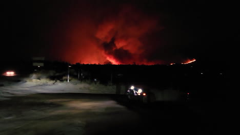 Vehículo-De-Cuatro-Ruedas-En-La-Noche-Moviéndose-En-La-Carretera-Del-Campo-Con-Llamas-De-Incendios-Forestales-En-El-Fondo,-Fairview,-California,-EE.UU.