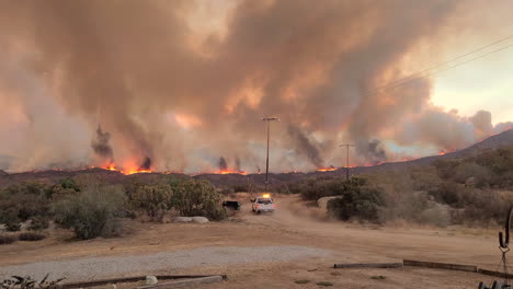 Emergency-vehicle-drives-by-flames-and-smoke-by-wildfire-in-California