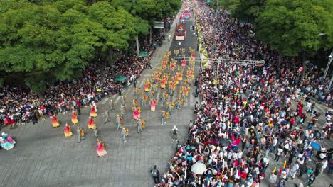 Vista-Aérea-De-Personas-Con-Trajes-Coloridos-Marchando-En-El-Desfile-Del-Día-De-Los-Muertos-En-La-Avenida-Reforma,-En-La-Ciudad-De-México