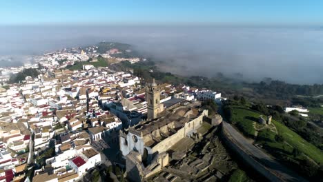 Drone-Aéreo-Disparó-Sobre-Medina-Sidonia-En-Andalucia-España-Con-Foco-En-La-Iglesia-De-Santa-María-Con-Vistas-Al-Casco-Antiguo-Y-Las-Nubes-En-Un-Día-Soleado