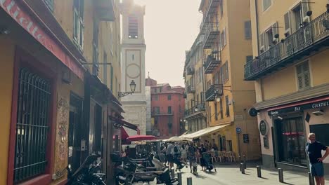 Crowd-Of-People-On-The-Street-In-Nice,-France-With-View-Of-Iconic-Bell-Tower-Of-Nice-Cathedral-In-Background