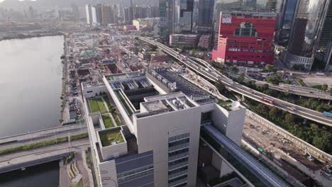 Un-Dron-Aéreo-Se-Disparó-Hacia-Atrás-Sobre-El-Equipo-Electromecánico-Del-Techo-Del-Hospital-Infantil-De-Hong-Kong,-China,-Con-Un-Intenso-Movimiento-De-Tráfico-En-El-Fondo-Al-Atardecer.