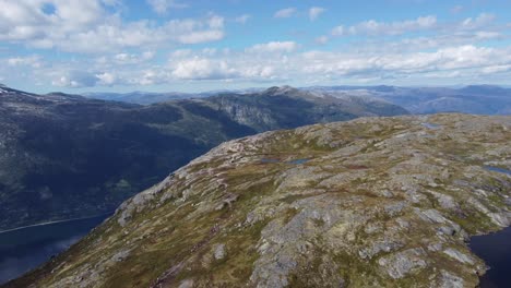 Long-crowded-line-of-people-is-walking-at-dronningstien-queens-hiking-trail-in-tall-mountain-landscape-between-Lofthus-and-Kinsarvik-in-Hardanger-Norway