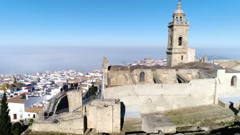 Toma-Aérea-De-La-Iglesia-De-Santa-María-En-Medina-Sidonia-En-Andalucia-En-España-Con-Vistas-Al-Casco-Histórico-Con-Edificios-Blancos-En-Un-Día-De-Verano-Sin-Nubes