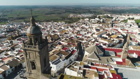 Toma-Panorámica-Aérea-Desde-La-Iglesia-De-Santa-María-Hasta-El-Casco-Antiguo-De-Medina-Sidonia-En-España-Con-Edificios-Principalmente-Blancos-En-Un-Hermoso-Día-Soleado