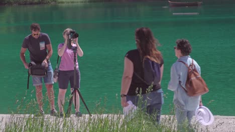 Una-Pareja-Profesional-Configurando-Su-Equipo-De-Fotografía-O-Video-Para-Una-Sesión-En-El-Lago-Braies,-Tirol-Del-Sur,-Italia