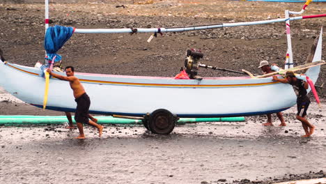 Gente-Empujando-Un-Pesado-Barco-Pesquero-Indonesio-Hacia-El-Agua-Del-Océano,-Vista-Lateral