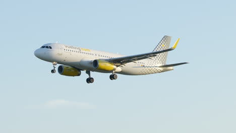 Vueling-air-plane-emerging-from-behind-tree-descending-into-Barcelona-at-sunrise