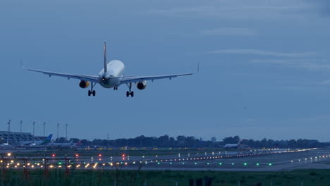 Hintere-Teleaufnahme-Eines-Vueling-Flugzeugs,-Das-Sich-Dem-Landeplatz-Am-Flughafen-Nähert,-Dämmerung