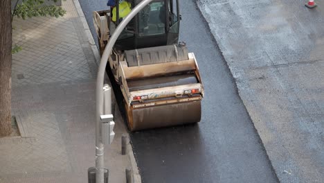 Vista-Desde-Arriba-De-Una-Máquina-Apisonadora-De-Doble-Tambor-Mientras-Se-Compacta-Asfalto-Recientemente-Colocado-En-Las-Calles-De-La-Ciudad