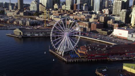 Vista-Aérea-Que-Rodea-La-Gran-Rueda-De-Seattle,-Revelando-El-Horizonte-De-La-Ciudad,-Hora-Dorada-En-El-Noroeste-De-Estados-Unidos