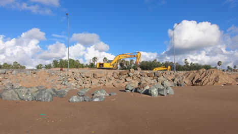 Bulldozer,-Der-Eine-Riesige-Mauer-Aus-Steinen-In-Der-Nähe-Eines-Strandes-Auf-Einer-Tropischen-Insel-Erstellt-Videohintergrund-|-Bulldozer-Maschine-Bei-Der-Arbeit-Für-Die-Entwicklung-Des-Strandes