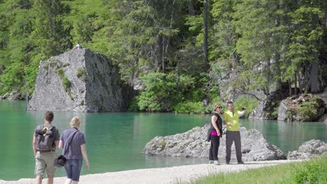 Groups-of-people-walking-by-and-taking-selfies-of-lake-Braies,-which-over-the-years-has-become-a-very-famous-tourist-destination