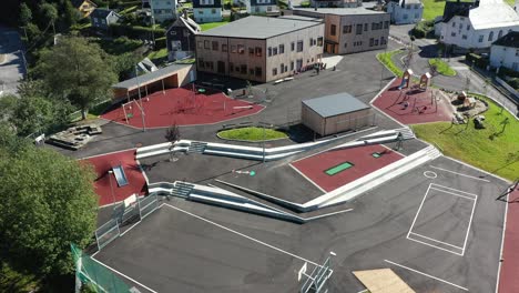 Patio-De-Recreo-E-Incline-Hacia-Arriba-Para-Revelar-El-Edificio-De-La-Escuela-Primaria-Vaksdal-En-Noruega---Antena-Con-Niños-Jugando-Afuera