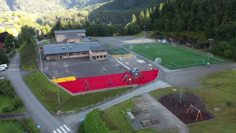 Muchos-Niños-Jugando-Dentro-De-La-Piscina-De-Bolas-De-Los-Patios-Escolares-De-Stanghelle---Antena-Fuera-De-Las-Instalaciones-Del-Patio-De-La-Escuela-Mirando-Hacia-Los-Niños-Y-El-Edificio---Noruega-Vaksdal