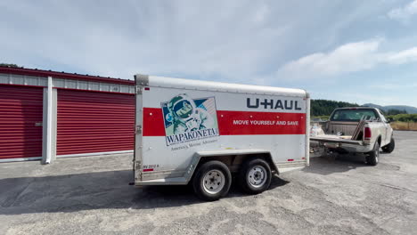 Hombre-En-Camioneta-Ford-Se-Aleja-Del-Cobertizo-De-Almacenamiento-Con-Un-Remolque-U-haul-A-Cuestas