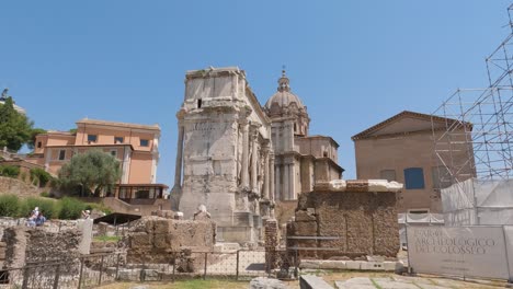 Visitors-walking-at-Septimius-Severus-Arch,-The-Roman-Forum,-Forum-Romanum,-surrounded-by-ruins-of-ancient-buildings,-Rome