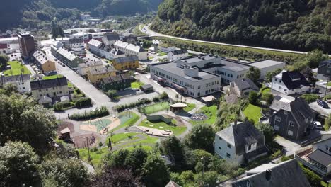 Nueva-Escuela-Primaria-Y-Secundaria-De-Dale-En-El-Municipio-De-Vaksdal-Noruega---Vista-Aérea-Del-Edificio-Con-El-Centro-De-Dale-Y-La-Carretera-E16-En-Segundo-Plano