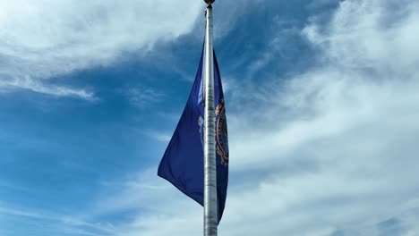 State-of-New-Hampshire-flag-waving-in-breeze-on-windy-day-against-blue-sky