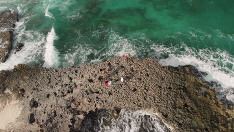 Gente-Visitando-Un-Acantilado-Rocoso-Rodeado-De-Olas-Peligrosas-En-México,-Inclinación-Aérea-Hacia-Arriba