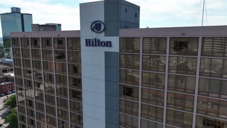 Aerial-view-in-front-of-the-Hilton-hotel-logo-in-downtown-Knoxville,-USA---descending,-tilt,-drone-shot