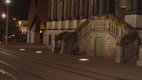 A-distant-violinist-plays-beautiful-music-in-front-of-a-historical-building-in-Ghent,-Belgium-at-night