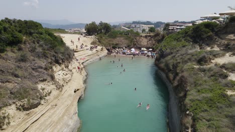 Sobrevuelo-Aéreo-Del-Canal-D&#39;amour-De-Corfú-En-Grecia,-La-Gente-Toma-El-Sol-Y-Nada-En-El-Canal-Del-Amor