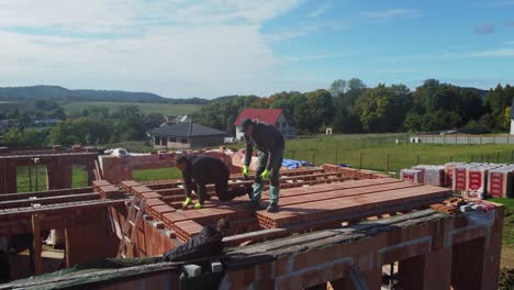 Bricklayers-building-new-flat-roof-of-bricks,-aerial-drone-side-closeup-view