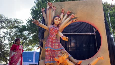 Mujer-De-Pie-Junto-Al-Hermoso-ídolo-De-Maa-Durga-Que-Está-Siendo-Transportado-Para-El-Rally-De-Inmersión-En-La-Carretera-Roja-Celebrado-En-Kolkata