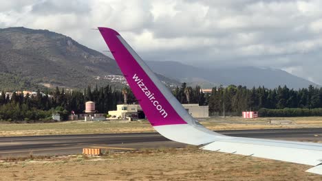 Nahaufnahme-Des-Flugzeugflügels-Mit-Dem-Wizz-Air-Logo,-Das-Auf-Dem-Rollfeld-Des-Flughafens-Rollt