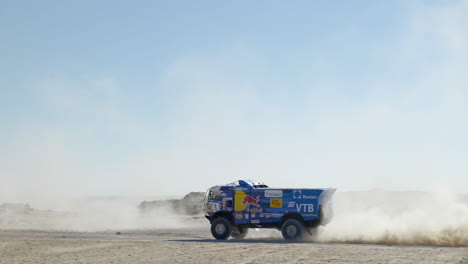 Big-Dakar-Rally-truck-driving-past-with-clouds-of-dusty-golden-sand-on-a-sunny-day