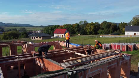 Workers-building-new-roof,-aerial-drone-closeup-view-of-construction-site