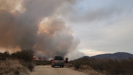 POV-shot-of-a-vehicle-travelling-along-a-dirt-road-approaching-a-safe-vantage-point-to-view-the-approaching-wildfire-known-as-the-Fairview-Fire-in-Hamlet,-California,-USA