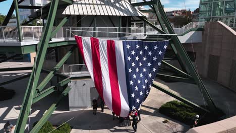 Vista-Aérea-Alrededor-De-La-Gente-Que-Levanta-La-Bandera-De-Los-Estados-Unidos-A-La-Torre-De-La-Esfera-Solar-En-Los-Estados-Unidos---Dando-Vueltas,-Tiro-De-Drones