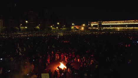 Aerial-view-over-a-crowd-having-a-bonfire-on-a-large-square-in-Mexico-city---low,-drone-shot