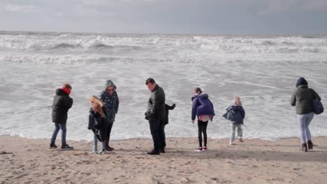 Vista-Trasera-De-La-Familia-Disfrutando-De-La-Ventosa-Playa-De-Otoño---De-Haan,-Bélgica