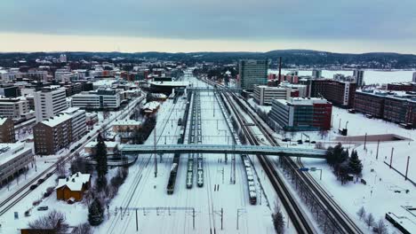 Vista-Aérea-De-Los-Trenes-En-La-Estación-De-Tren-En-Jyvaskyla,-Nublado,-Noche-De-Invierno-En-Finlandia---Descendiendo,-Disparo-De-Drones