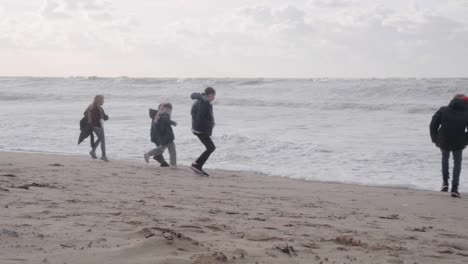 Glückliche-Kinder,-Die-Vor-Dem-Meerwasser-Davonlaufen,-Das-Von-Der-Belgischen-Nordsee-An-Land-Kommt