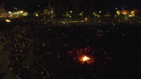 Luftaufnahme-über-Demonstranten,-Die-Auf-Einem-Großen-Stadtplatz-Ein-Lagerfeuer-Haben---Neigung,-Drohnenschuss