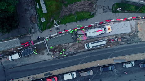 Toma-Aérea-De-Arriba-Hacia-Abajo-Del-Sitio-De-Construcción-En-La-Ciudad-Con-Construcción-De-Camiones-Y-Grúas-De-La-Calle-De-Asfalto