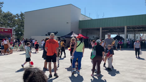 Gran-Multitud-De-Personas-En-Un-Evento-De-Demostración-De-Seguridad-Y-Fuego-De-Casa-Abierta-En-La-Casa-De-Bomberos-Con-Un-Camión-De-Bomberos-Y-Una-Ambulancia-En-Exhibición-Para-Que-El-Público-Los-Vea,-Tampa-Florida,-Tiro-Panorámico