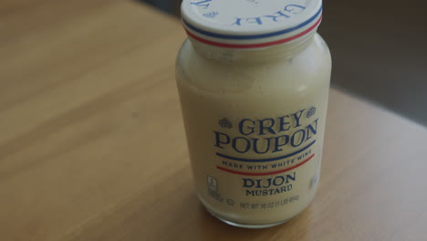 Cerrar-La-Bandeja-A-La-Derecha-De-Un-Frasco-De-Mostaza-Dijon-Poupon-Gris