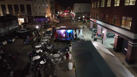 Vista-Aérea-Hacia-Una-Banda-Tocando-En-Las-Calles-De-Cincinnati-Iluminada,-Festival-De-Parpadeo-En-Ohio,-Estados-Unidos