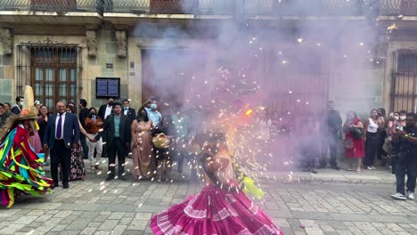 Toma-En-Cámara-Lenta-De-Una-Mujer-Indígena-Con-Trajes-Tradicionales-De-Oaxaca-Y-Fuegos-Artificiales-Morados-En-La-Cabeza-Durante-Una-Celebración-De-Boda-En-La-Ciudad-De-Oaxaca-México