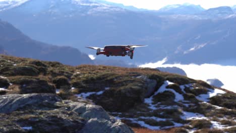 Modern-drone-hovering-in-front-of-camera-before-rotating-and-flying-away-to-disappear-into-vast-mountain-landscape---Nesheim-mountain-in-Vaksdal-Norway---Dji-mavic-2-drone-with-Hasselblad-camera